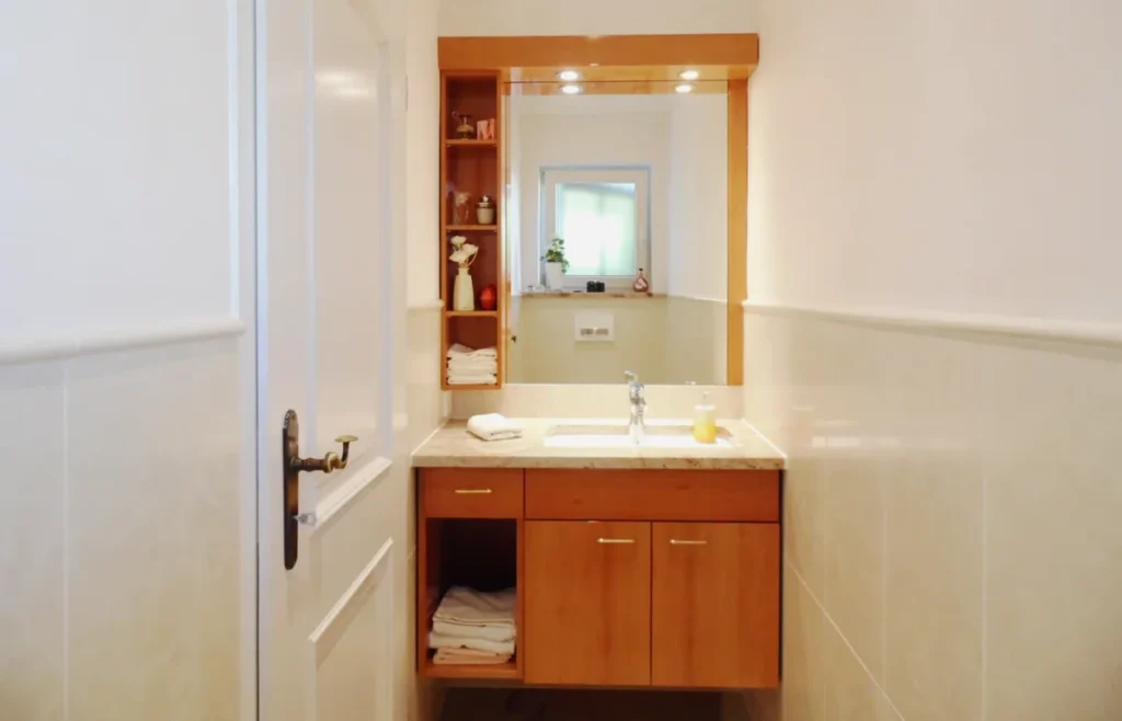 Maßgefertigtes Badmöbel aus Birnbaum hochglanz lackiert mit Waschbecken, Spiegel und offenem Regal in einem schmalen Bad