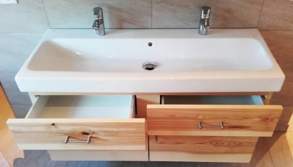 Maßgefertigter Waschtischunterschrank aus Esche unter Keramik-Waschbecken, Schubladen und Auszug geöffnet.