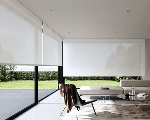 Ein modernes Wohnzimmer mit großen Fenstern und MHZ-Rollos als Sonnenschutz. Der Raum ist minimalistisch eingerichtet, mit einem schwarzen Sessel, einem Couchtisch und einem Sofa, und bietet einen Blick ins Grüne.