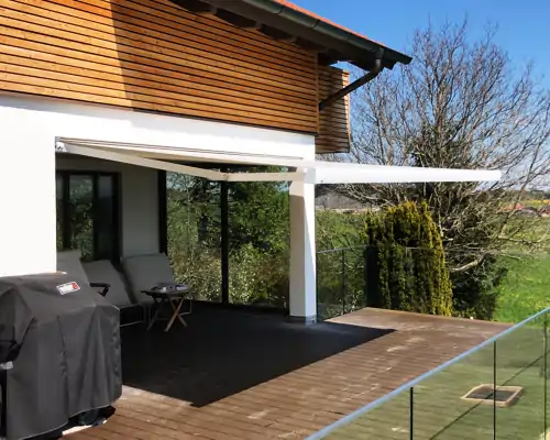Outdoor Sonnenschutz auf einer modernen Holzterrasse – elektrische Markise spendet Schatten an einem sonnigen Tag.
