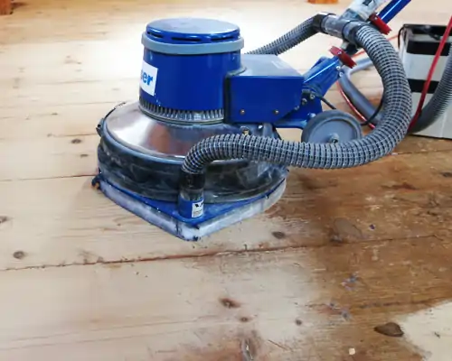Parkettboden wird mit einer professionellen Schleifmaschine bearbeitet, um die Oberfläche zu glätten und aufbereiten.