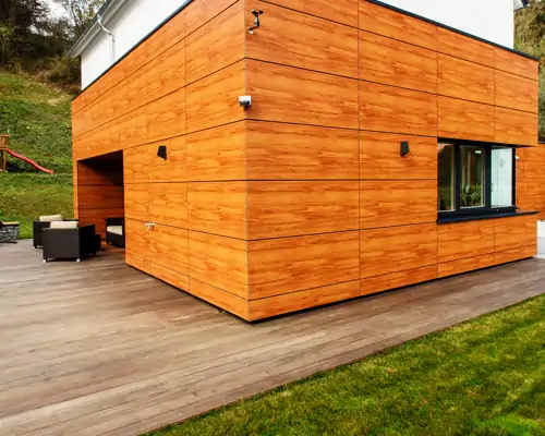 Großzügige Holzterrasse mit moderner Fassadenverkleidung aus Holz, Eckterrasse mit Garten und Loungemöbeln