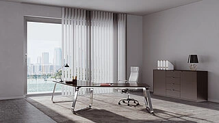 Helles Büro mit großem Fenster, das eine Stadtansicht zeigt. Vor dem Fenster hängt ein weißer MHZ Lamellenvorhang als Blendschutz. Im Raum steht ein moderner Schreibtisch mit Glasplatte und Metallbeinen, darauf liegen einige Gegenstände. Ein weißer Bürostuhl mit Rollen steht am Schreibtisch. Rechts an der Wand befindet sich ein Sideboard mit mehreren weißen Ordnern und einer schwarzen Tischlampe.