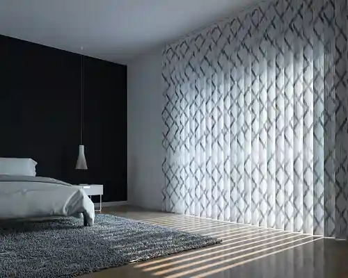 Schlafzimmer mit großem Fenster, das mit MHZ Lamellenvorhängen in weiß mit grauem Rautenmuster bedeckt ist. Links ein Bett mit weißer Bettwäsche, daneben ein weißer Nachttisch und eine hängende Lampe. Der Boden ist hell und mit einem dunkelgrauen Teppich bedeckt. Die Lamellenvorhänge lassen Lichtstreifen auf den Boden fallen.