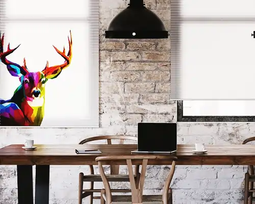 Esszimmer mit MHZ Plissee freihängend von oben an zwei Fenstern, eines mit farbigem Hirschmotiv, Holztisch mit Laptop, Tassen und Stühlen vor weißer Backsteinwand, schwarze Hängeleuchte