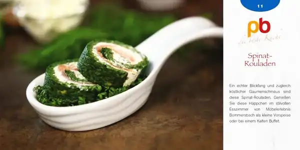 Die Abbildung zeigt zwei grüne Spinat-Rouladen, die auf einem weißen, länglichen Löffel angerichtet sind. Die Rouladen sind aufgerollt und haben eine helle Füllung, die sich spiralförmig im Inneren zeigt. Im Hintergrund sind unscharf grüne Kräuter und ein helles Gemüse zu erkennen. Rechts neben dem Bild befindet sich ein Textblock mit dem Titel 'Spinat-Rouladen' und einer kurzen Beschreibung des Gerichts. Logo 'pb die beste Küche'