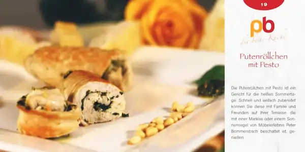 Das Bild zeigt ein Putensandwich, das in der Mitte durchgeschnitten ist, sodass die Füllung mit grünem Pesto sichtbar wird. Das Sandwich liegt auf einem weißen Teller, daneben sind einige Pinienkerne verteilt. Im Hintergrund ist unscharf eine orangefarbene Rose zu erkennen. Rechts neben dem Teller ist ein Rezeptkartenausschnitt mit dem Titel 'Putensröllchen mit Pesto' zu sehen, darunter ein kurzer Text, der das Gericht als schnell und einfach zubereitet beschreibt und zum Genießen auf der Terrasse einlädt.