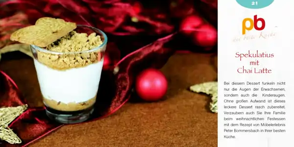 Glas mit Schichtdessert, bestehend aus einer dunklen Schicht am Boden, einer weißen Schicht in der Mitte und einer bröseligen, hellbraunen Schicht obenauf. Daneben liegen zerbrochene Spekulatius-Kekse. Im Hintergrund rote Weihnachtsdekoration mit Kugeln und Stoffband. Rechts oben Text mit dem Titel 'Spekulatius mit Chai Latte' und einer kurzen Beschreibung des Desserts, die auf die einfache Zubereitung und den Genuss bei Weihnachtsfesten hinweist.