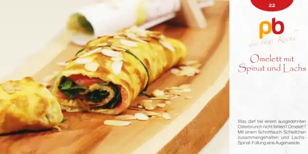 Omelettrolle mit Spinat und Lachs, garniert mit Mandelblättchen, auf Holzbrett mit Messer im Hintergrund, Rezeptkarte mit Text 'Omelett mit Spinat und Lachs' und Logo 'pb die beste Küche'