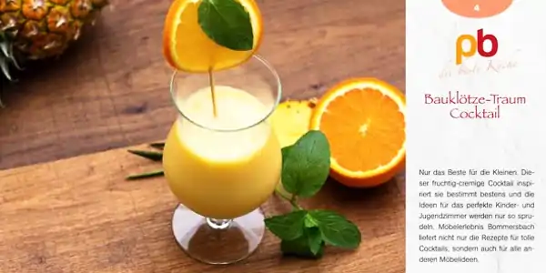 Cocktailglas mit gelbem Getränk, garniert mit Orangenscheibe und Minzblatt, auf Holztisch neben halbierter Orange und Ananas, Rezeptkarte mit Titel 'Bauklötze-Traum Cocktail' und kurzem Text.