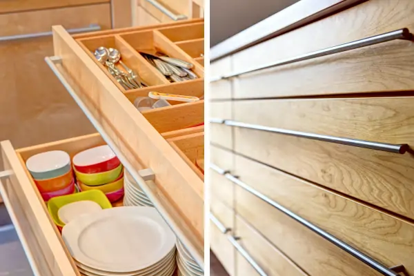 Links geöffnete Schubladen einer Schreinerküche mit Massivholzfronten. Die obere Schublade enthält Besteck und Küchenutensilien, die untere Schublade ist mit gestapeltem Geschirr und bunten Schalen gefüllt. Rechts eine Nahaufnahme der Massivholzfront mit horizontal verlaufenden, silberfarbenen Griffleisten.