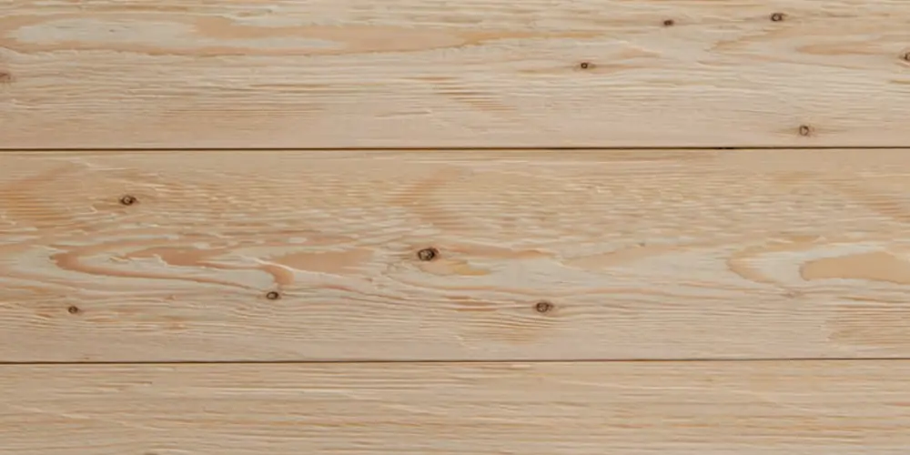 Nahaufnahme von gehacktem und gebürstetem Lärchenholz mit strukturierter Oberfläche, warm-goldbrauner Farbgebung und ausgeprägter Maserung.