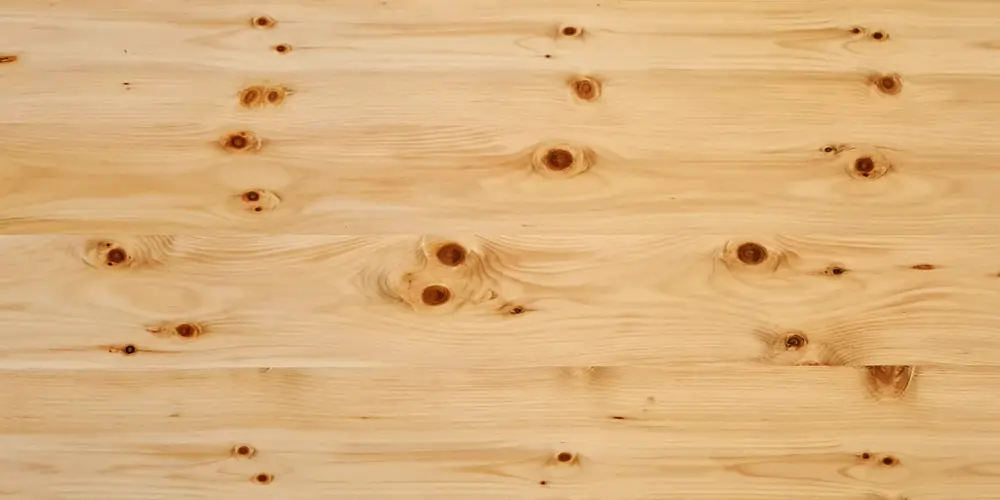 Zirbelkiefer-Holzoberfläche mit heller, warm-gelblicher Farbe, sichtbarer Maserung und markanten Astpunkten – dekoratives Zirbenholz für Möbel und Innenausbau.