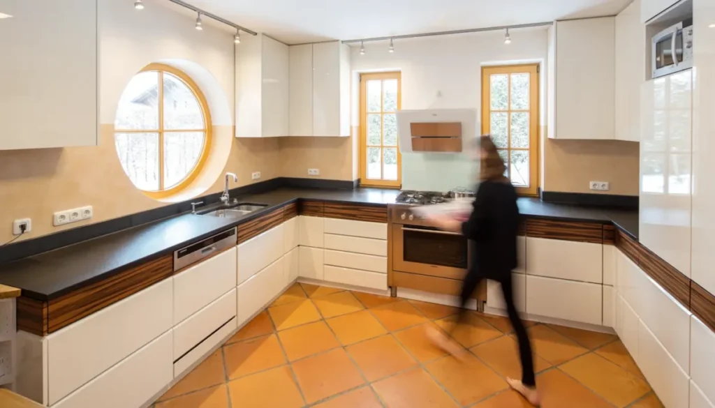 Grifflose Hochglanzküche im offenen Wohnbereich in Altenstadt mit schwarzer Natursteinplatte und rundem Fenster