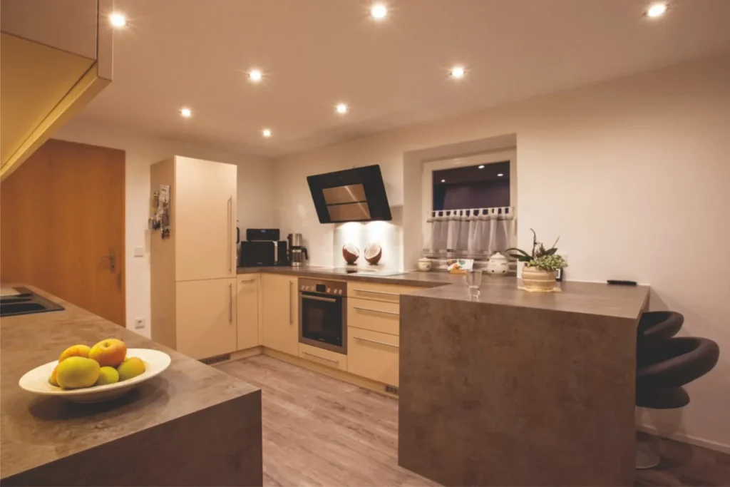 Großzügige Küche in Peißenberg mit Theke, langen Edelstahl-Stangengriffen und Schichtstoff-Arbeitsplatte nach Maß